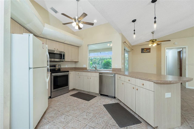 kitchen with lofted ceiling, sink, decorative light fixtures, stainless steel appliances, and kitchen peninsula