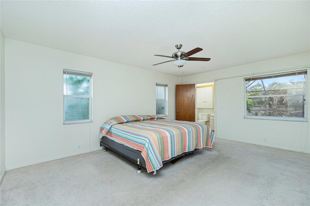 bedroom featuring ceiling fan, light carpet, and a textured ceiling