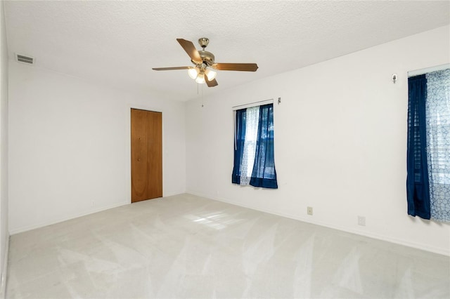 unfurnished room featuring ceiling fan, carpet, and a textured ceiling