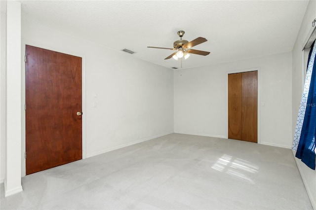 carpeted spare room with a textured ceiling and ceiling fan