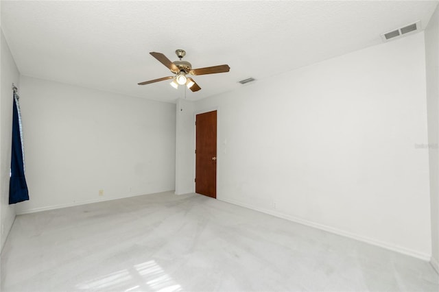 empty room featuring light carpet, ceiling fan, and a textured ceiling