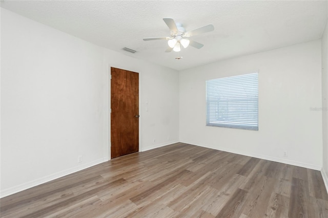 spare room featuring a textured ceiling, ceiling fan, and light hardwood / wood-style flooring