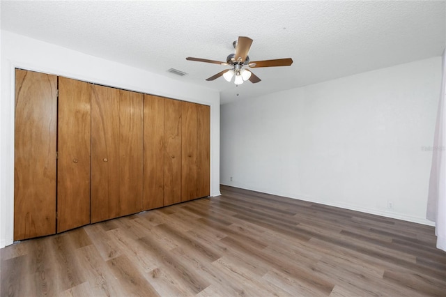 unfurnished bedroom with a textured ceiling, a closet, ceiling fan, and light hardwood / wood-style flooring