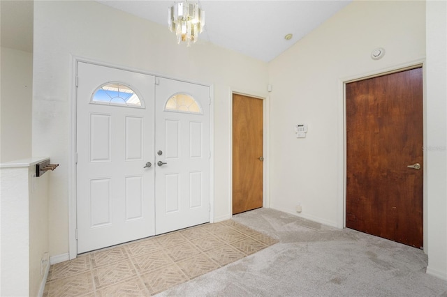 carpeted foyer entrance with lofted ceiling and a notable chandelier