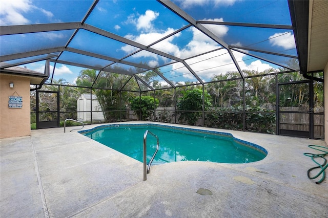 view of pool with a storage shed, glass enclosure, and a patio area