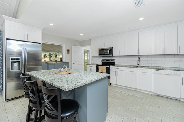 kitchen featuring sink, stainless steel appliances, white cabinetry, and a center island