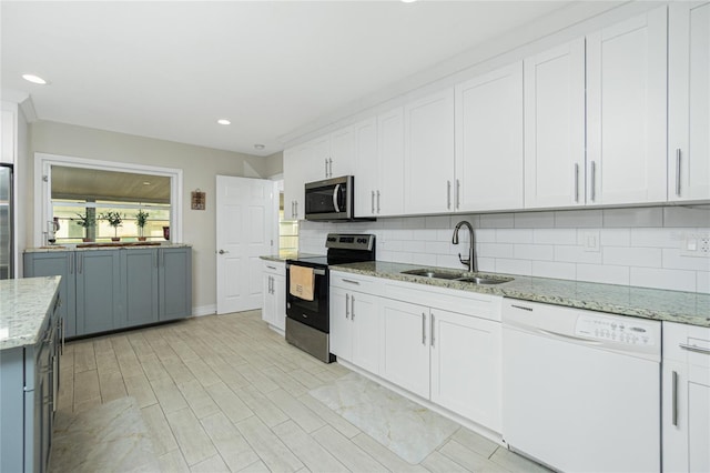 kitchen featuring appliances with stainless steel finishes, sink, backsplash, light stone counters, and white cabinets