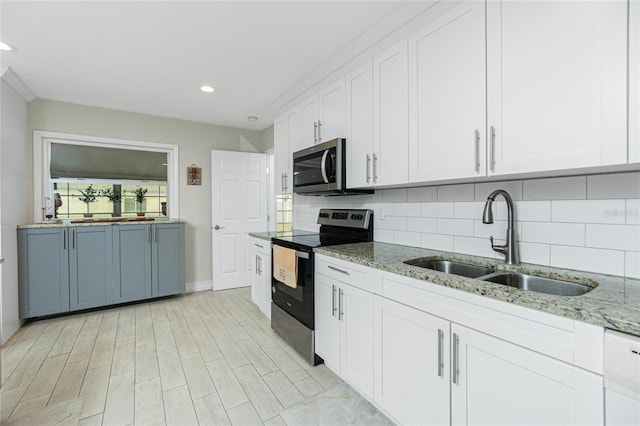 kitchen featuring white cabinetry, light stone countertops, sink, tasteful backsplash, and appliances with stainless steel finishes