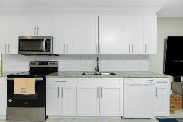 kitchen with sink, appliances with stainless steel finishes, white cabinetry, and light stone counters