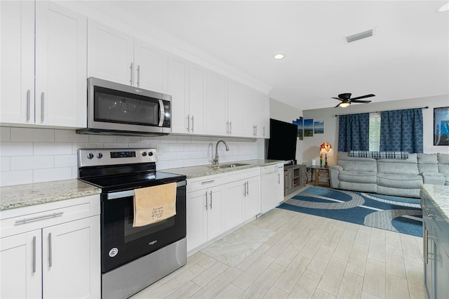 kitchen featuring appliances with stainless steel finishes, sink, light stone counters, white cabinets, and decorative backsplash