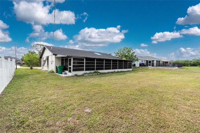 back of property with a lawn and a sunroom