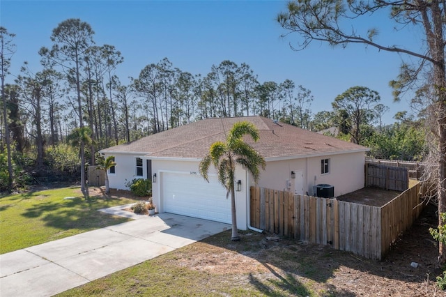 view of property exterior featuring a yard, fence, concrete driveway, and stucco siding