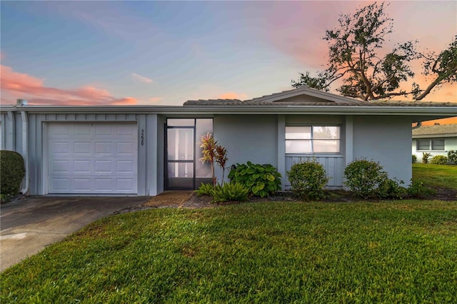 ranch-style house with a garage and a lawn