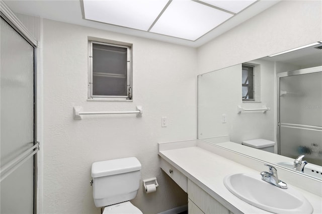 bathroom featuring vanity, a shower with door, and toilet