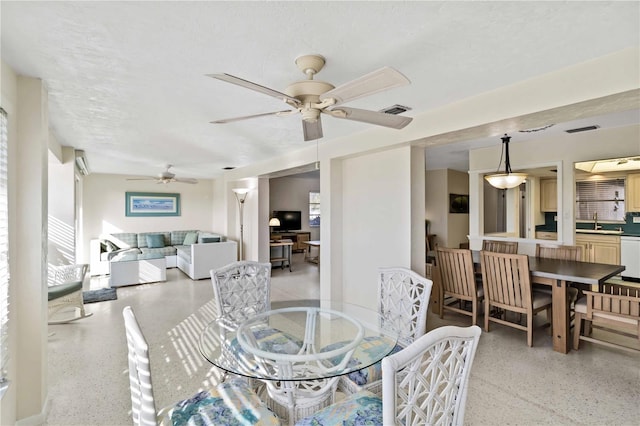 dining area with ceiling fan, sink, and a textured ceiling