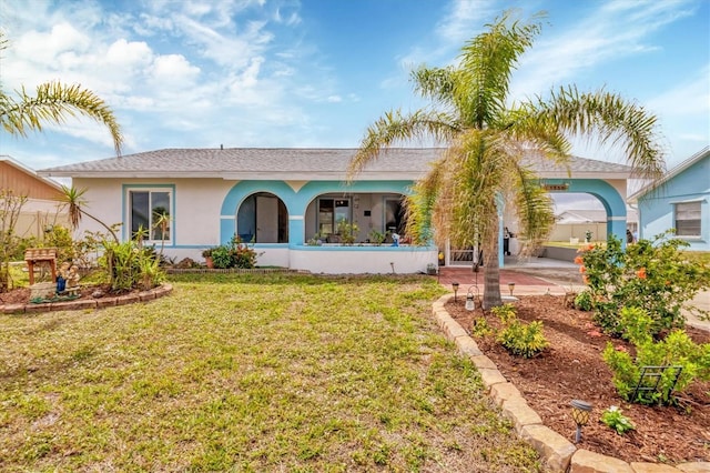 rear view of property featuring a yard and stucco siding