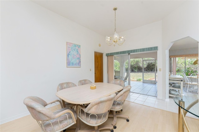 dining room featuring a chandelier, arched walkways, baseboards, and light wood-style floors