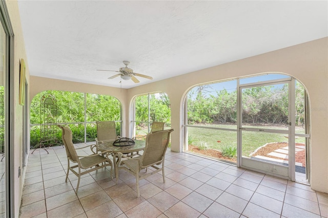 sunroom / solarium featuring outdoor dining space, tile patterned floors, and a ceiling fan