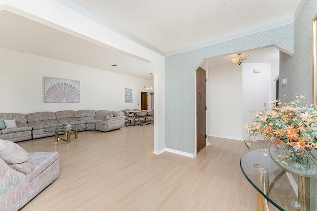 living room with wallpapered walls, light wood finished floors, an inviting chandelier, and crown molding
