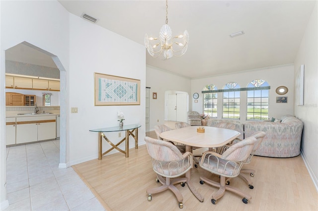 dining space with arched walkways, light tile patterned floors, a notable chandelier, and visible vents