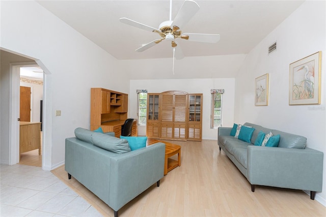 living room with arched walkways, a ceiling fan, visible vents, lofted ceiling, and light wood finished floors