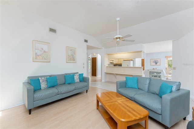 living area with vaulted ceiling, a ceiling fan, light wood-style floors, visible vents, and arched walkways