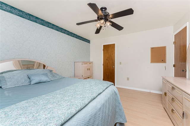 bedroom featuring light wood-style floors, baseboards, wallpapered walls, and ceiling fan