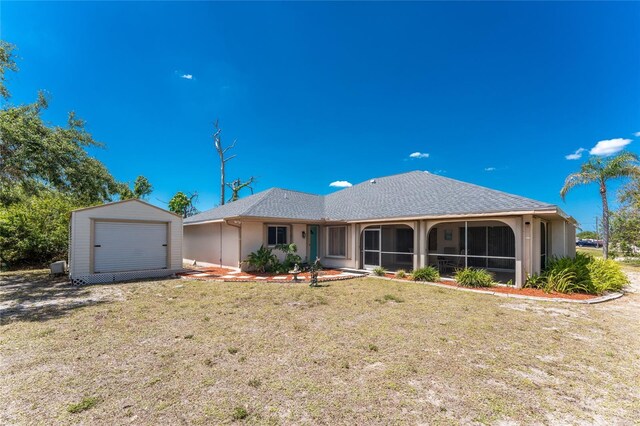 view of front of house featuring a front yard, stucco siding, an outdoor structure, and a sunroom