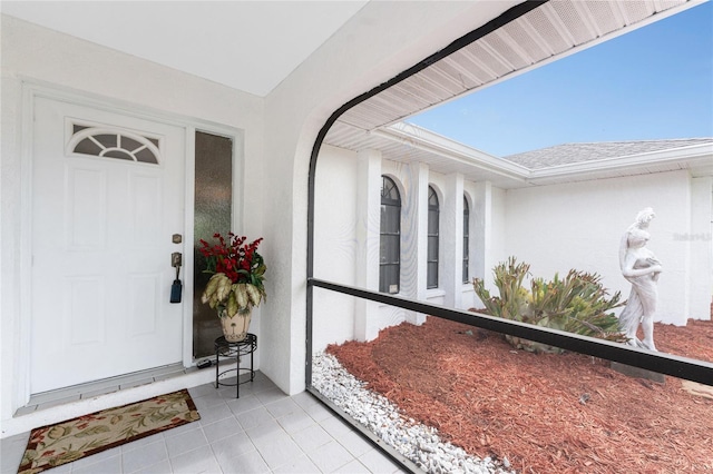 doorway to property with a shingled roof and stucco siding