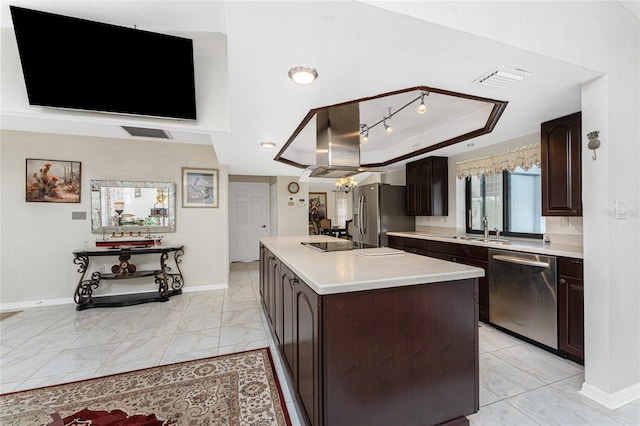 kitchen with a kitchen island with sink, stainless steel appliances, marble finish floor, light countertops, and a raised ceiling