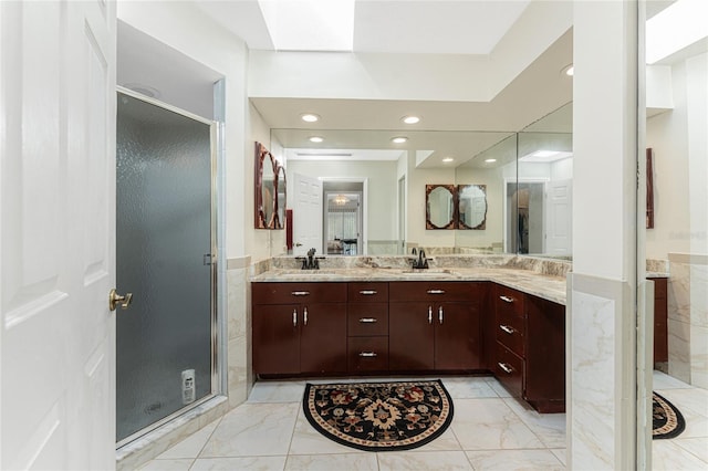 bathroom with marble finish floor, a sink, and a stall shower