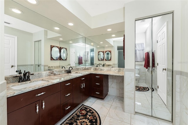 bathroom with marble finish floor, double vanity, a sink, and toilet