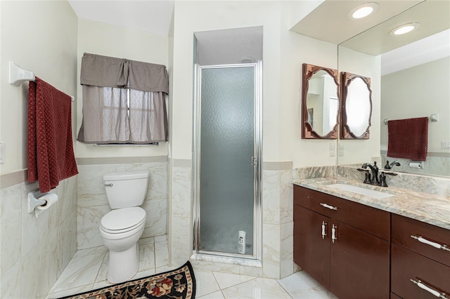 bathroom with toilet, a wainscoted wall, vanity, tile walls, and a shower stall