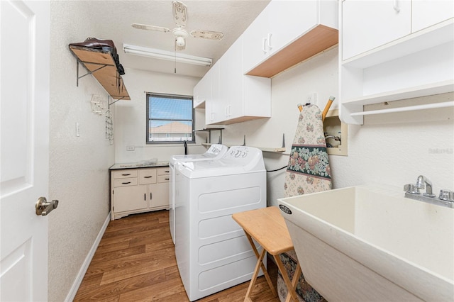 laundry room featuring a sink, baseboards, light wood-type flooring, cabinet space, and washer and clothes dryer