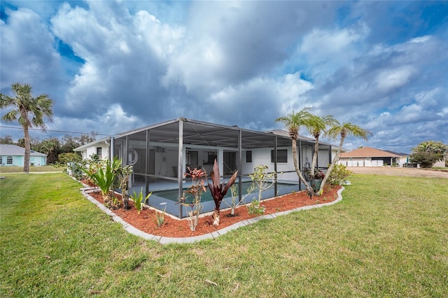 rear view of house with glass enclosure, a lawn, and an outdoor pool