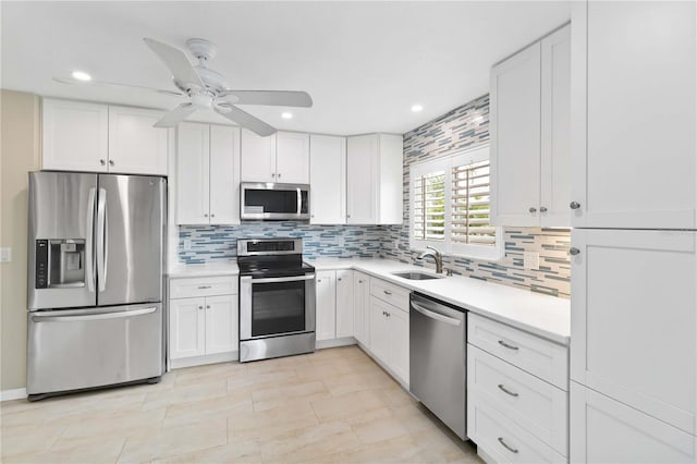 kitchen featuring stainless steel appliances, white cabinets, light countertops, and a sink