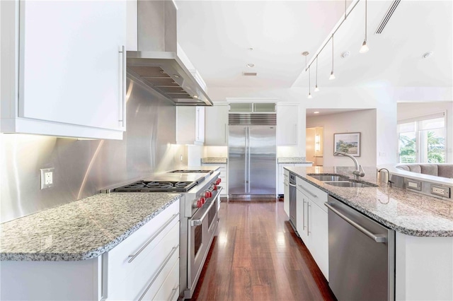 kitchen with sink, island range hood, premium appliances, pendant lighting, and white cabinets