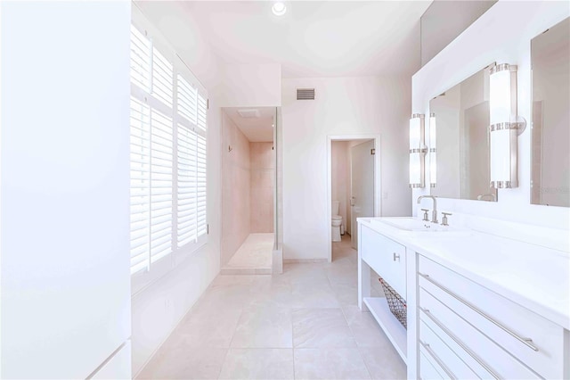 bathroom with vanity, toilet, and a tile shower