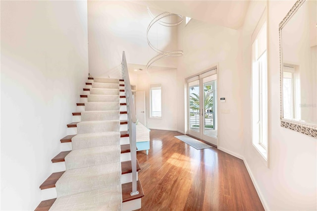 foyer entrance with french doors, a towering ceiling, and hardwood / wood-style floors