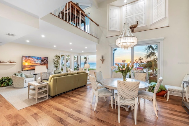 dining space with a chandelier, light hardwood / wood-style flooring, and a high ceiling