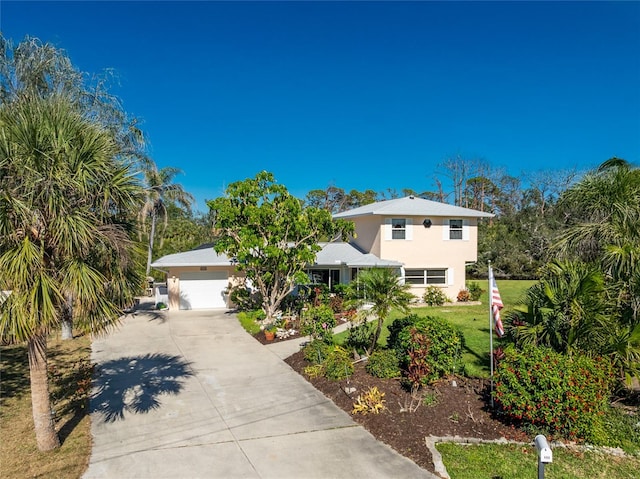 view of front of house featuring a garage, a front yard, concrete driveway, and stucco siding