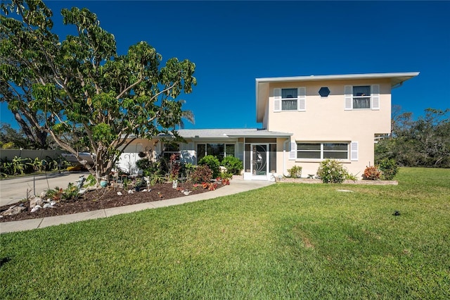 traditional home with driveway, a front lawn, and stucco siding