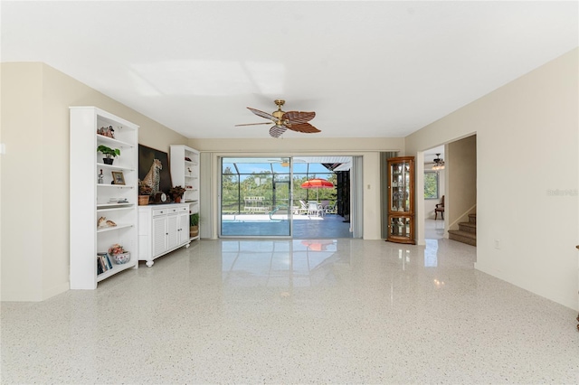 unfurnished living room with ceiling fan, speckled floor, and a sunroom