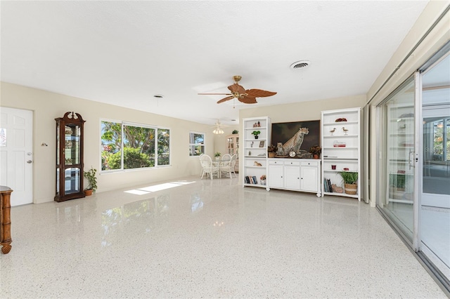 unfurnished living room with a textured ceiling, speckled floor, visible vents, and a ceiling fan