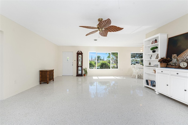 unfurnished living room featuring light speckled floor and ceiling fan