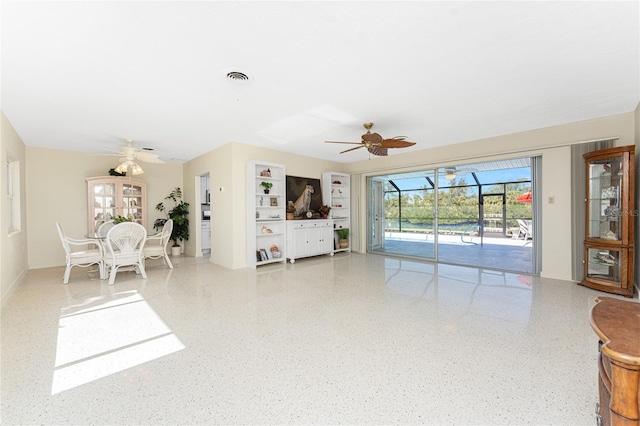 living room with ceiling fan, a sunroom, speckled floor, and visible vents