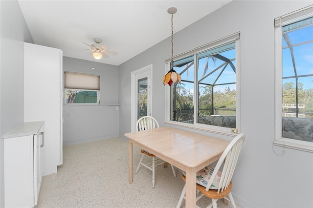 dining area featuring a sunroom, baseboards, and a ceiling fan