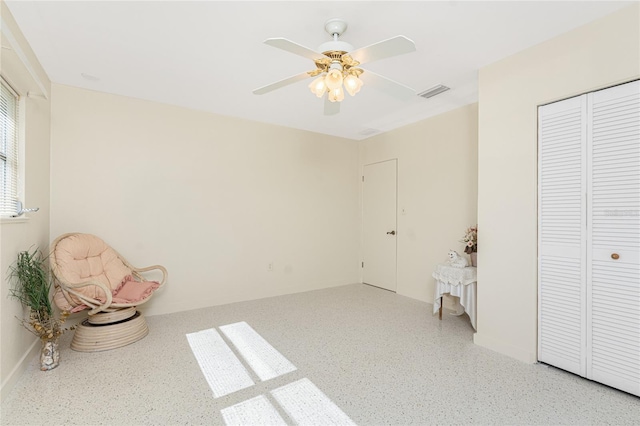 unfurnished room with visible vents, ceiling fan, and speckled floor