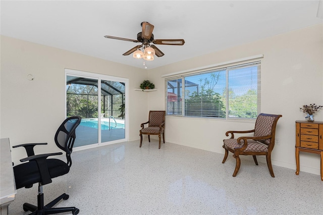 office space featuring a sunroom, ceiling fan, baseboards, and speckled floor