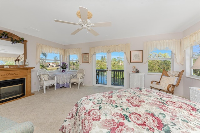 bedroom with access to exterior, multiple windows, carpet flooring, and a glass covered fireplace